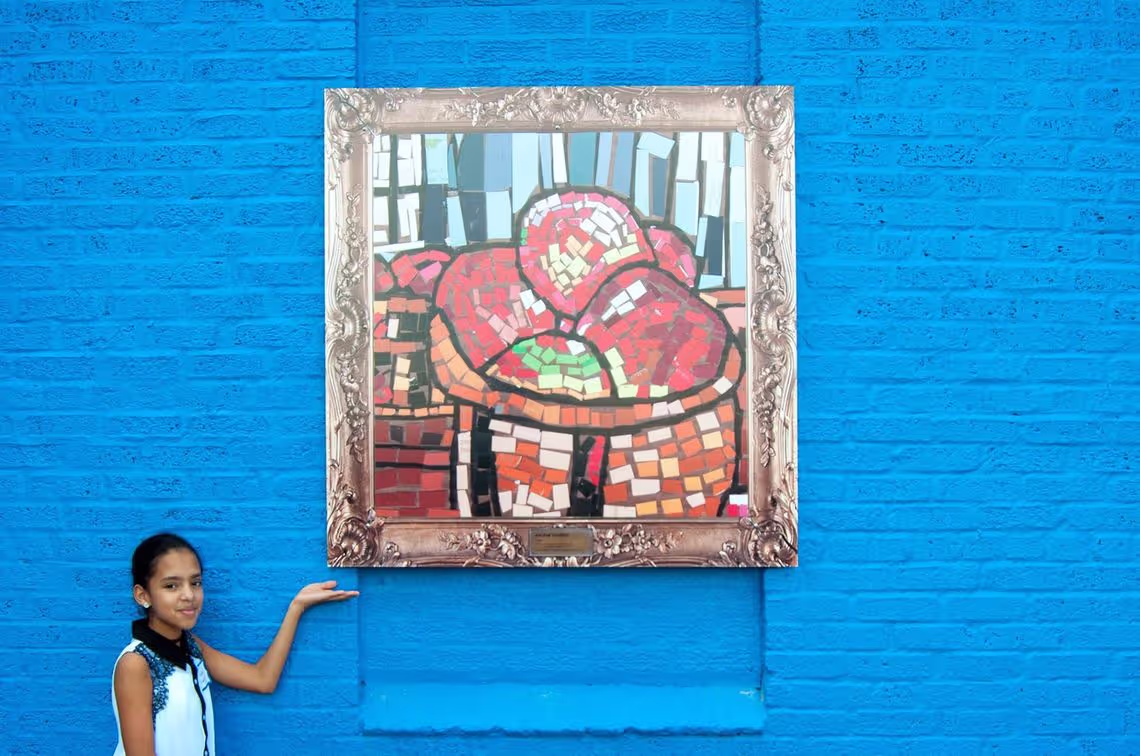 A girl pointing at a painting on a blue wall